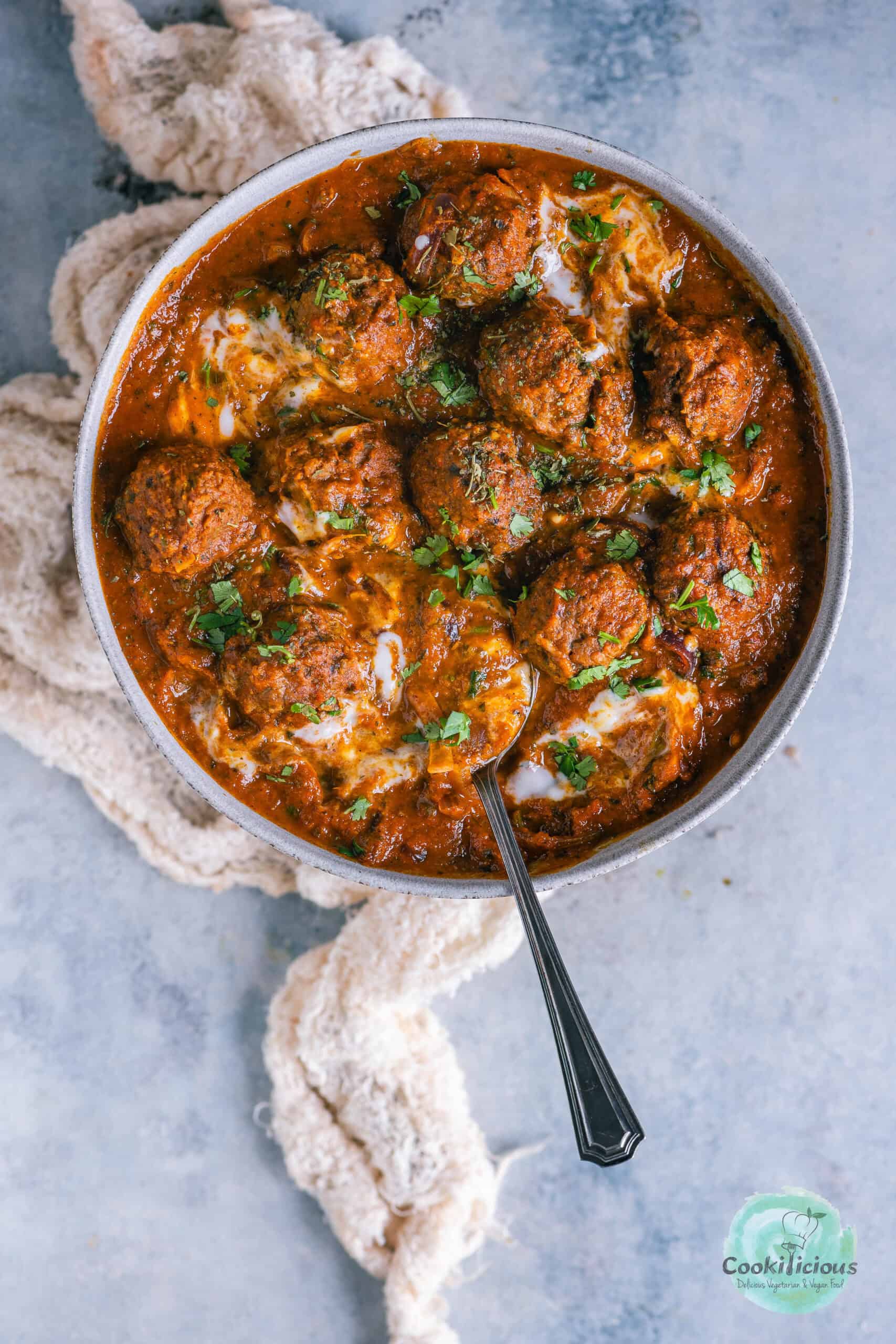 Kofta Curry with Plant-Based Meatballs served in a bowl with a spoon in it.