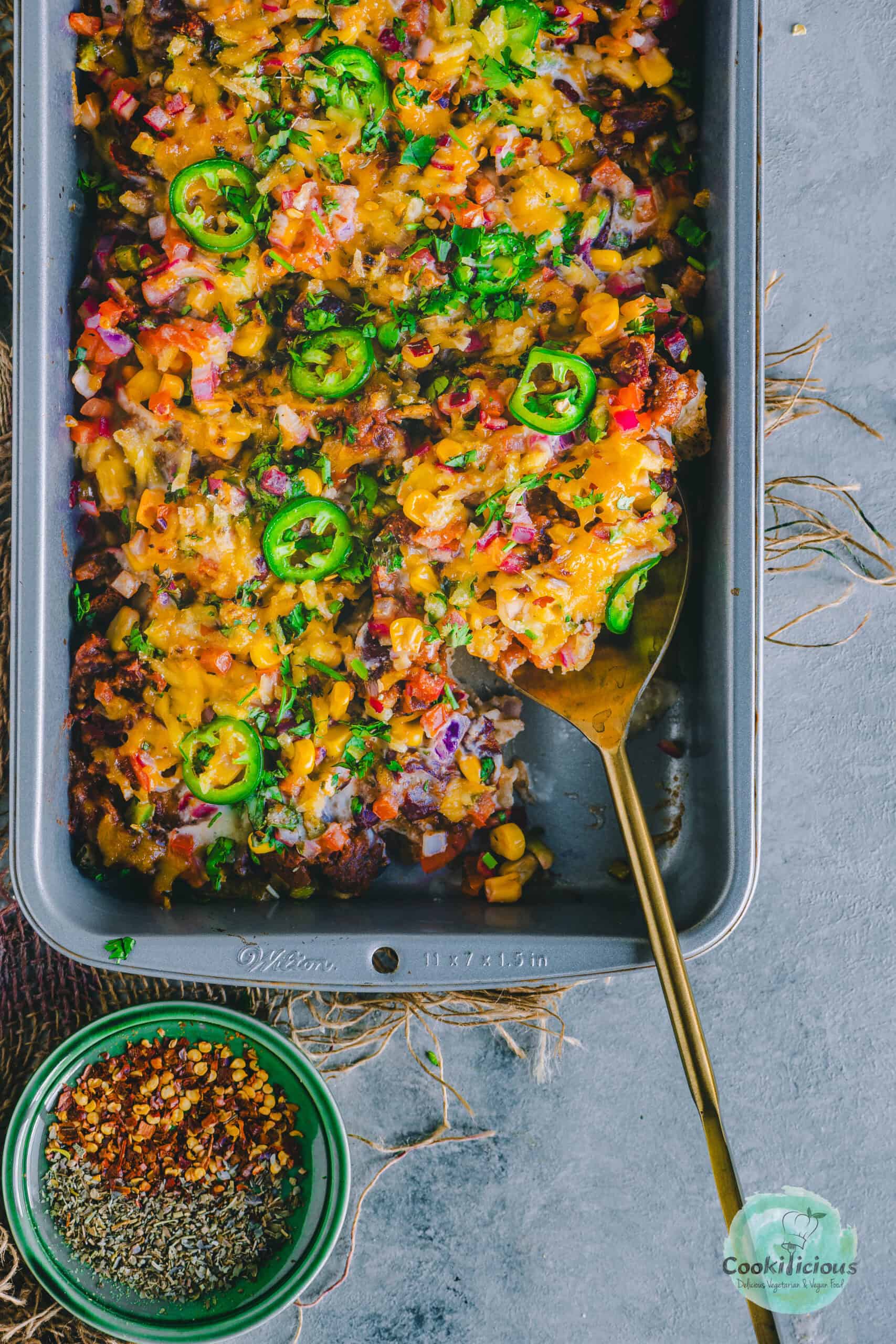 a spoon inside the tray of Vegan Loaded Nachos .