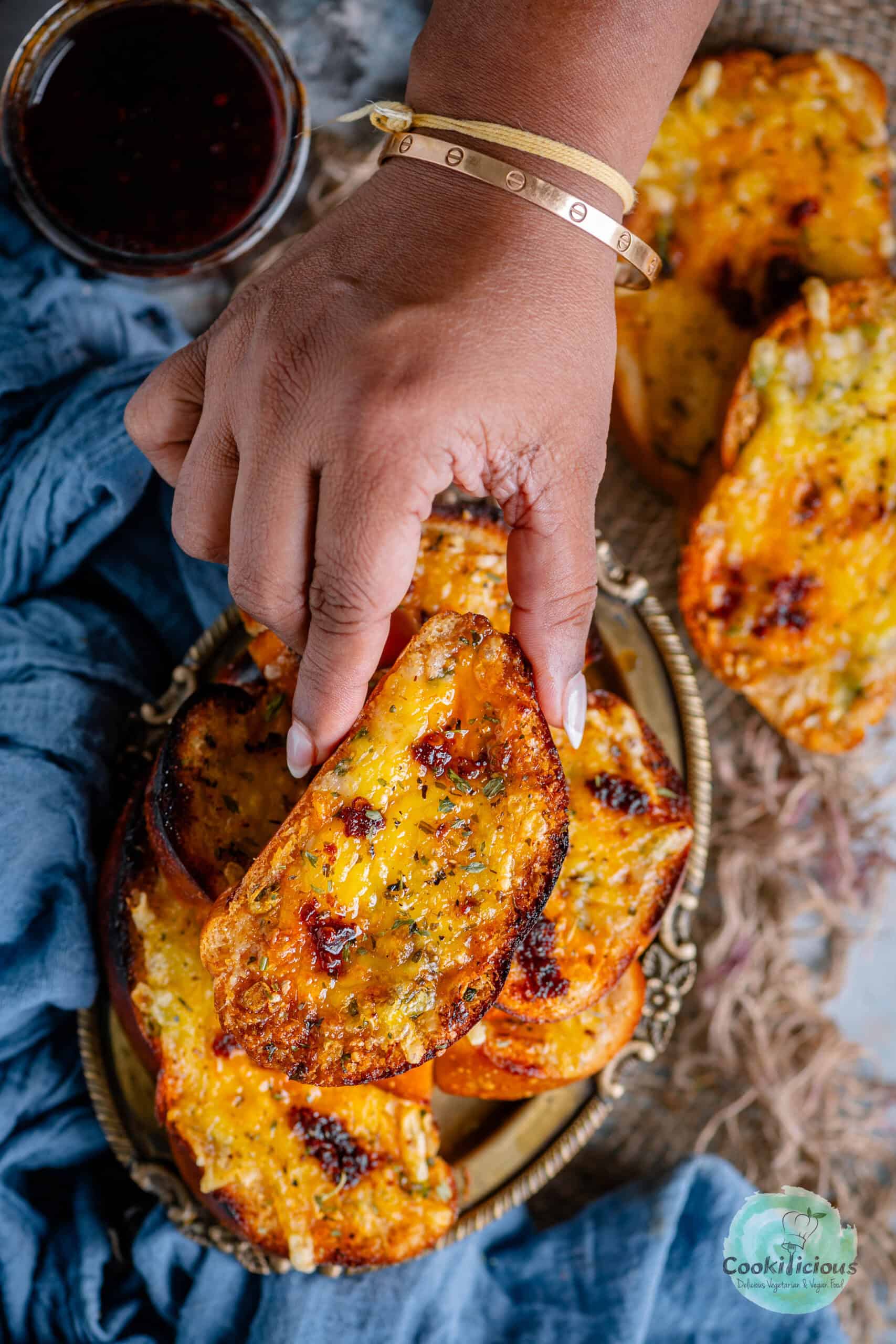 A hand holding one vegan garlic bread.