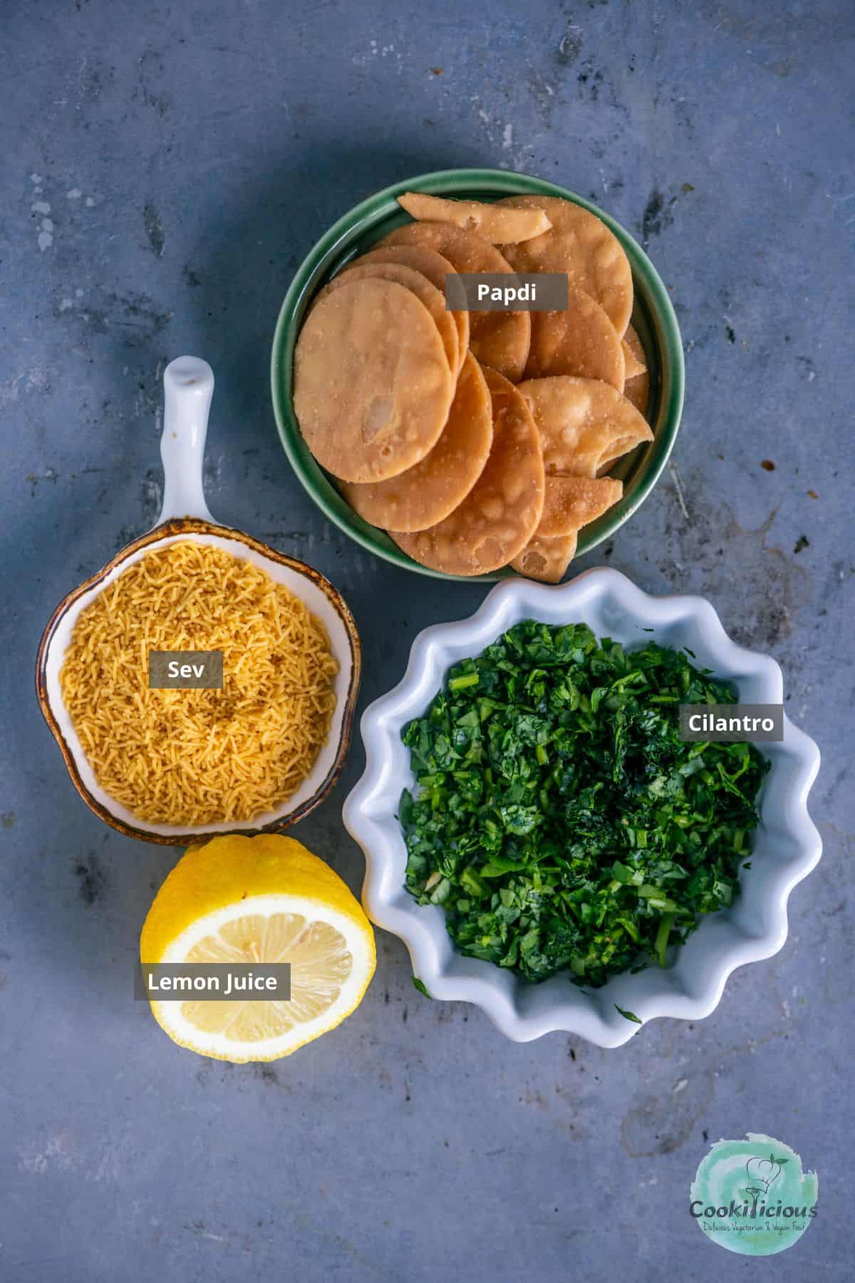 all the ingredients needed to garnish Bhelpuri placed on a table with labels on them.