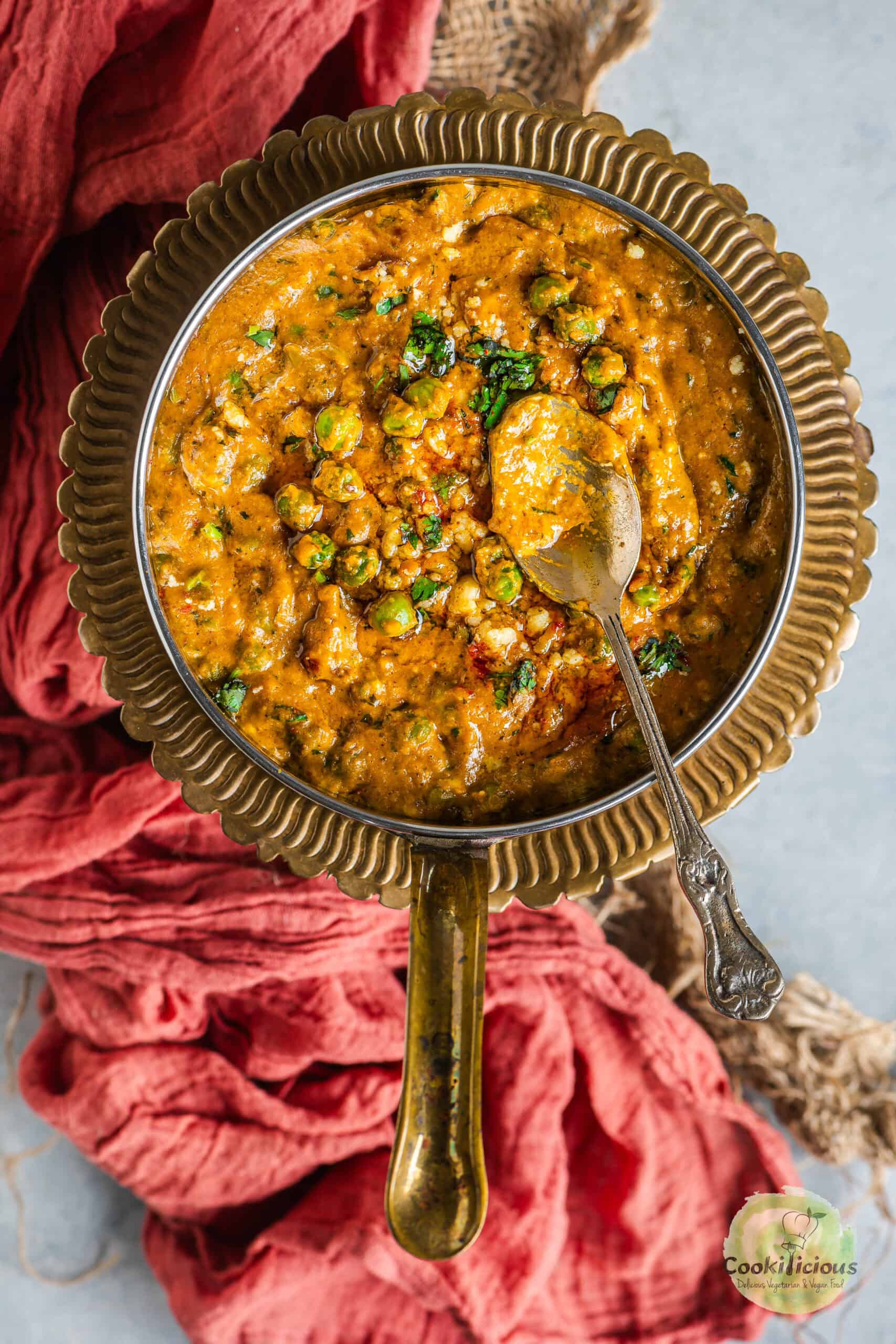 A spoon placed on top of Khoya Matar curry.