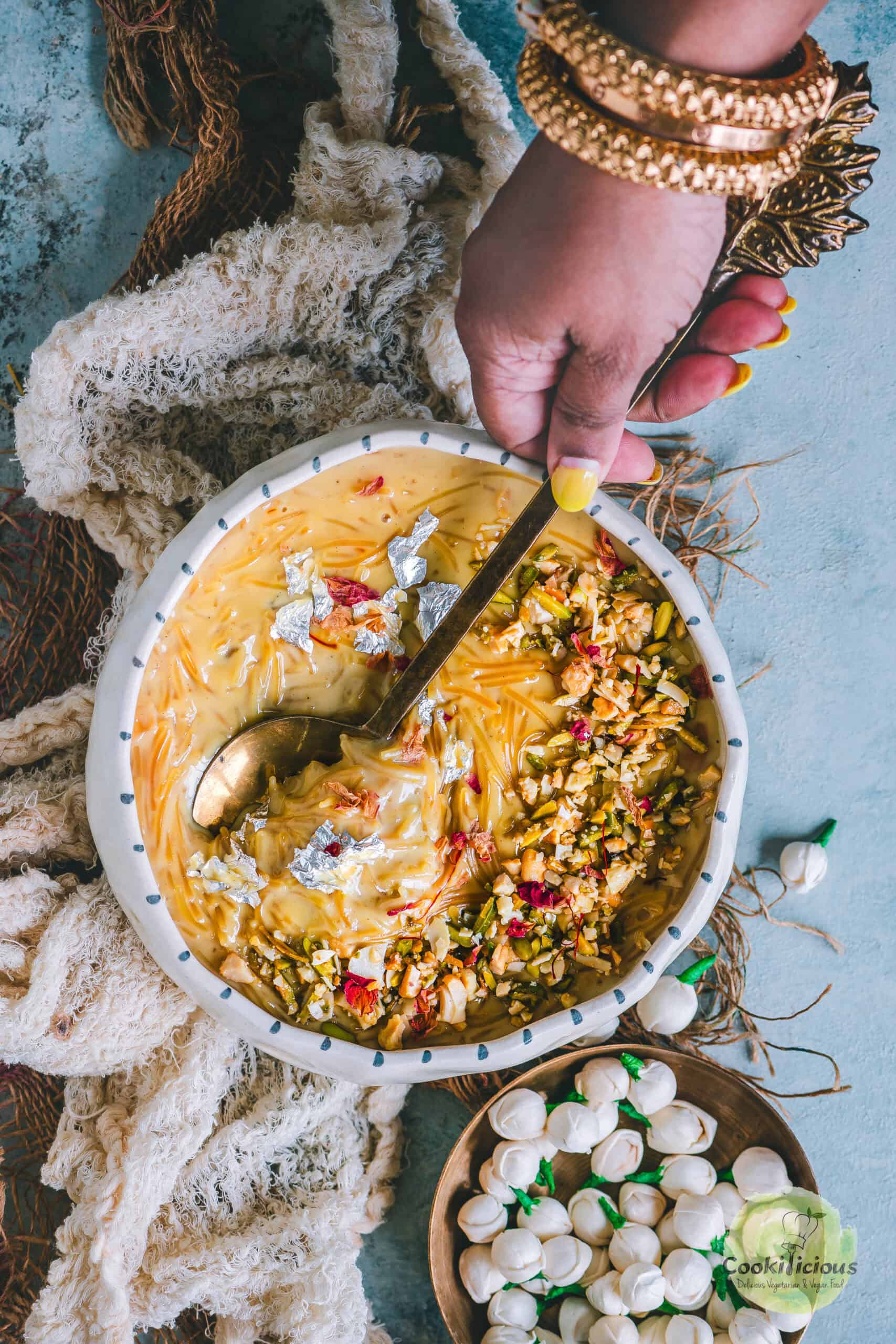 A hand digging into a bowl of Seviyan Kheer with a spoon.