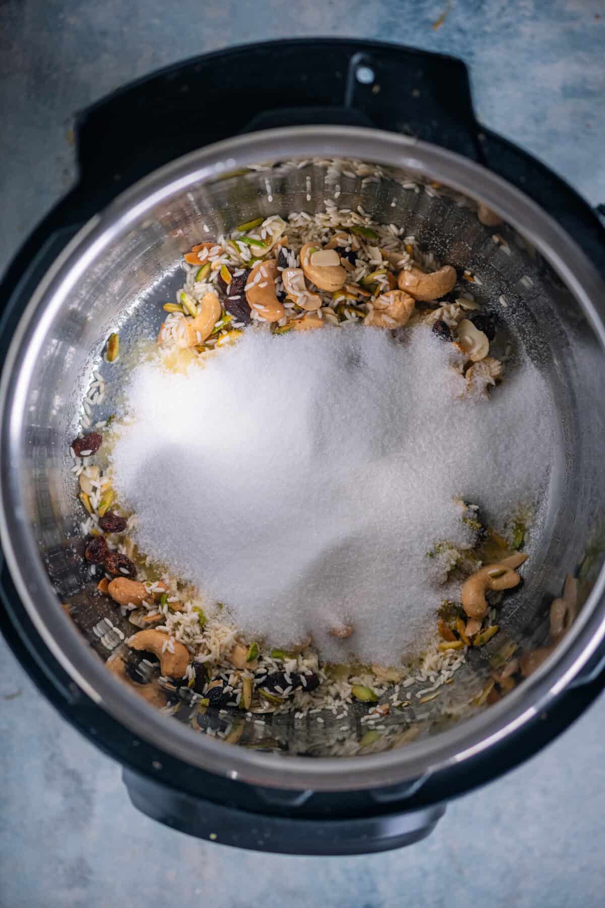 Sugar being stirred into toasted rice in an Instant Pot.