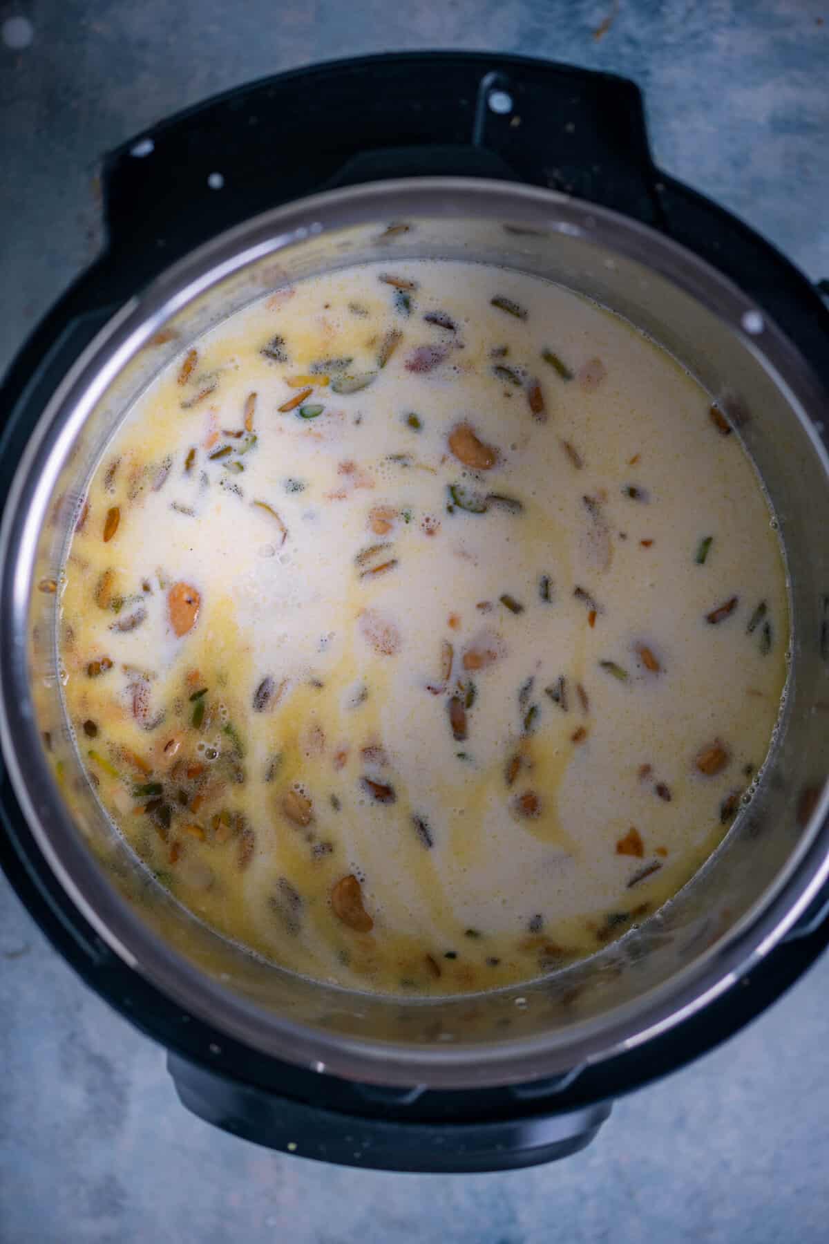 Whole milk and heavy cream being poured into the Instant Pot with rice and sugar.