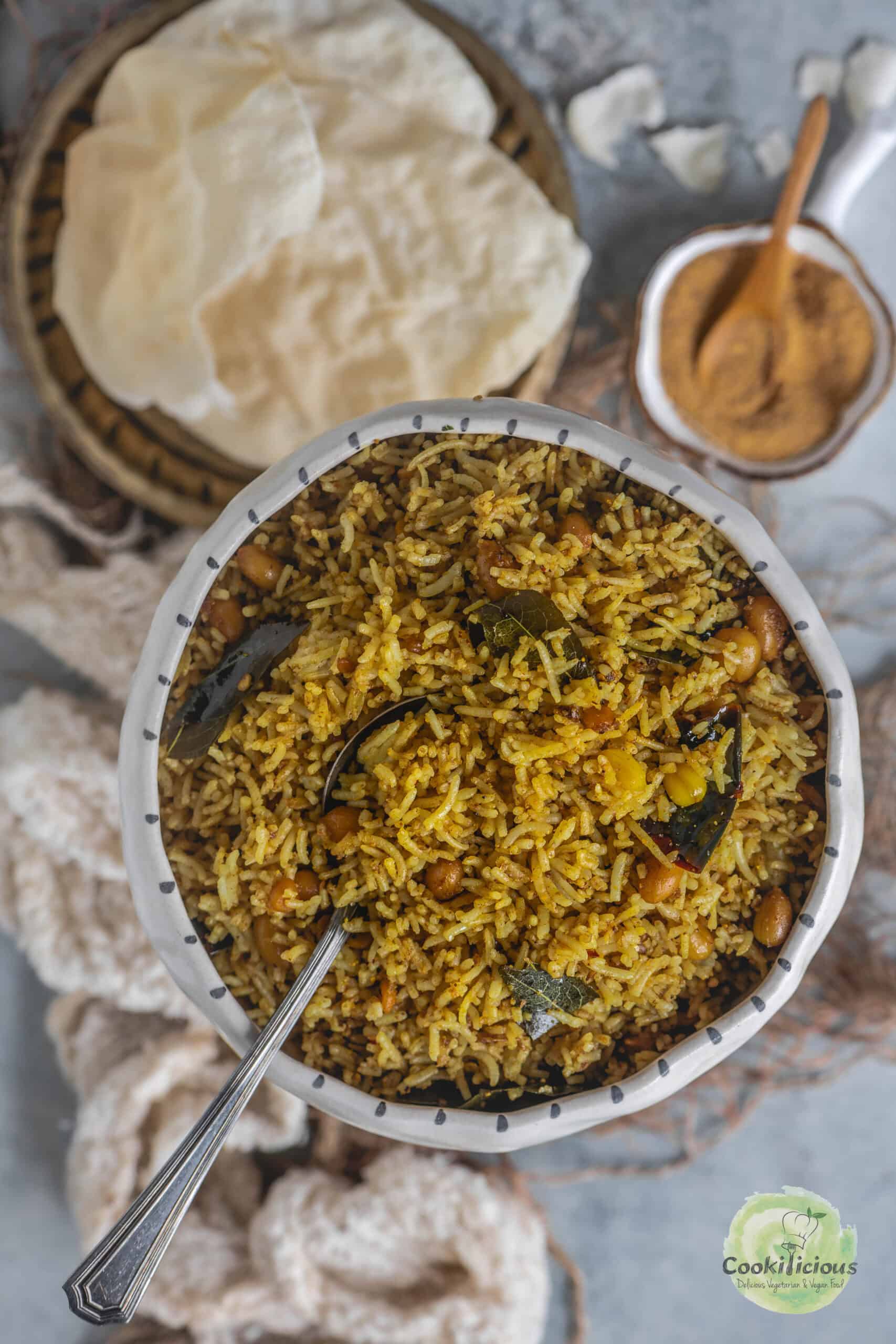 A bowl of tangy and aromatic Puliyogare with tamarind paste and roasted nuts.