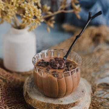 Indulgent vegan chocolate mousse served in a mini jar with a spoon in it.