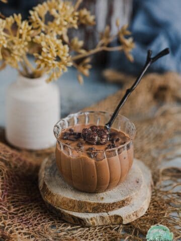 Indulgent vegan chocolate mousse served in a mini jar with a spoon in it.