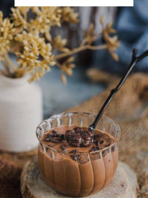 Indulgent vegan chocolate mousse served in a mini jar with a spoon in it and text at the top.