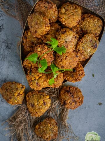 Golden-brown crispy dal vadas stacked on a plate, garnished with fresh cilantro.