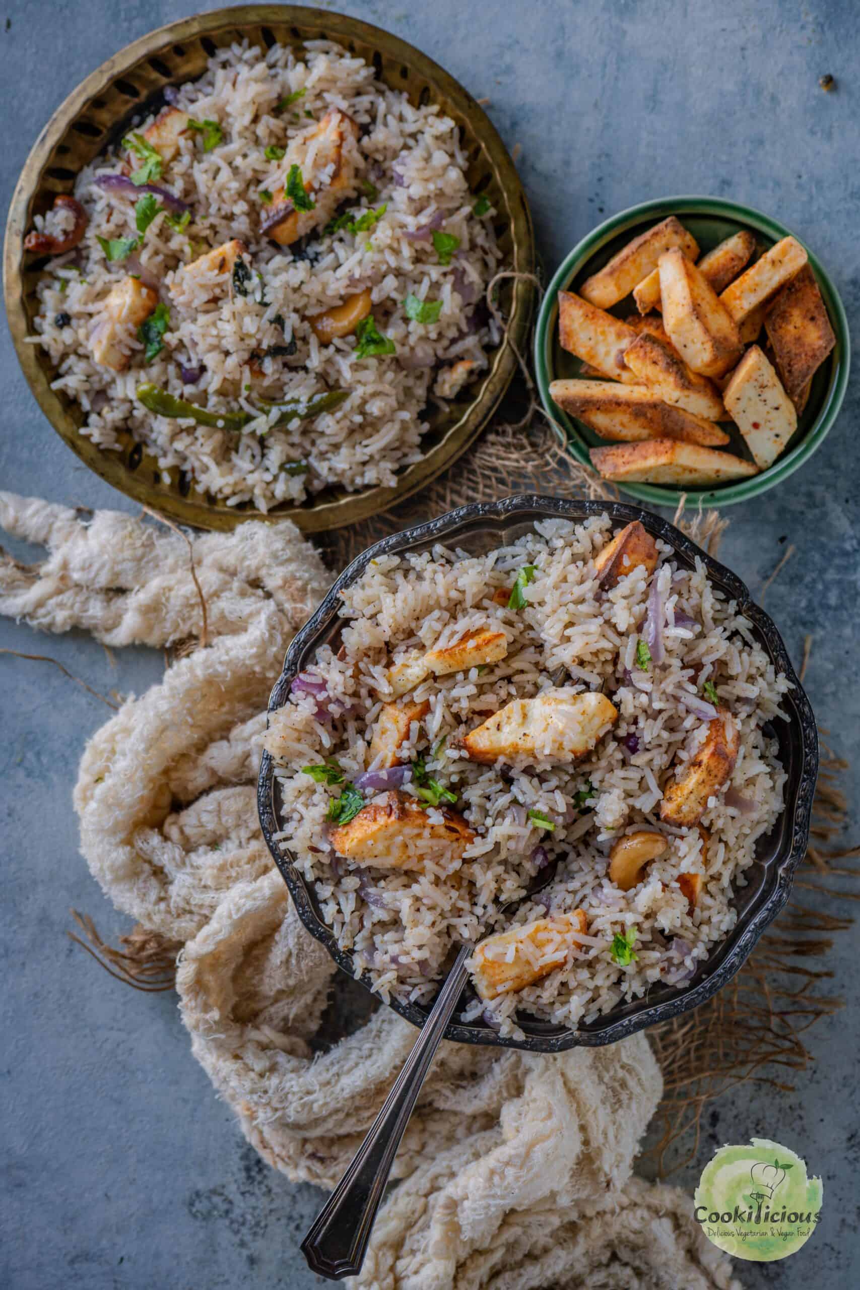 two plates filled with paneer pulao topped with air fried paneer.