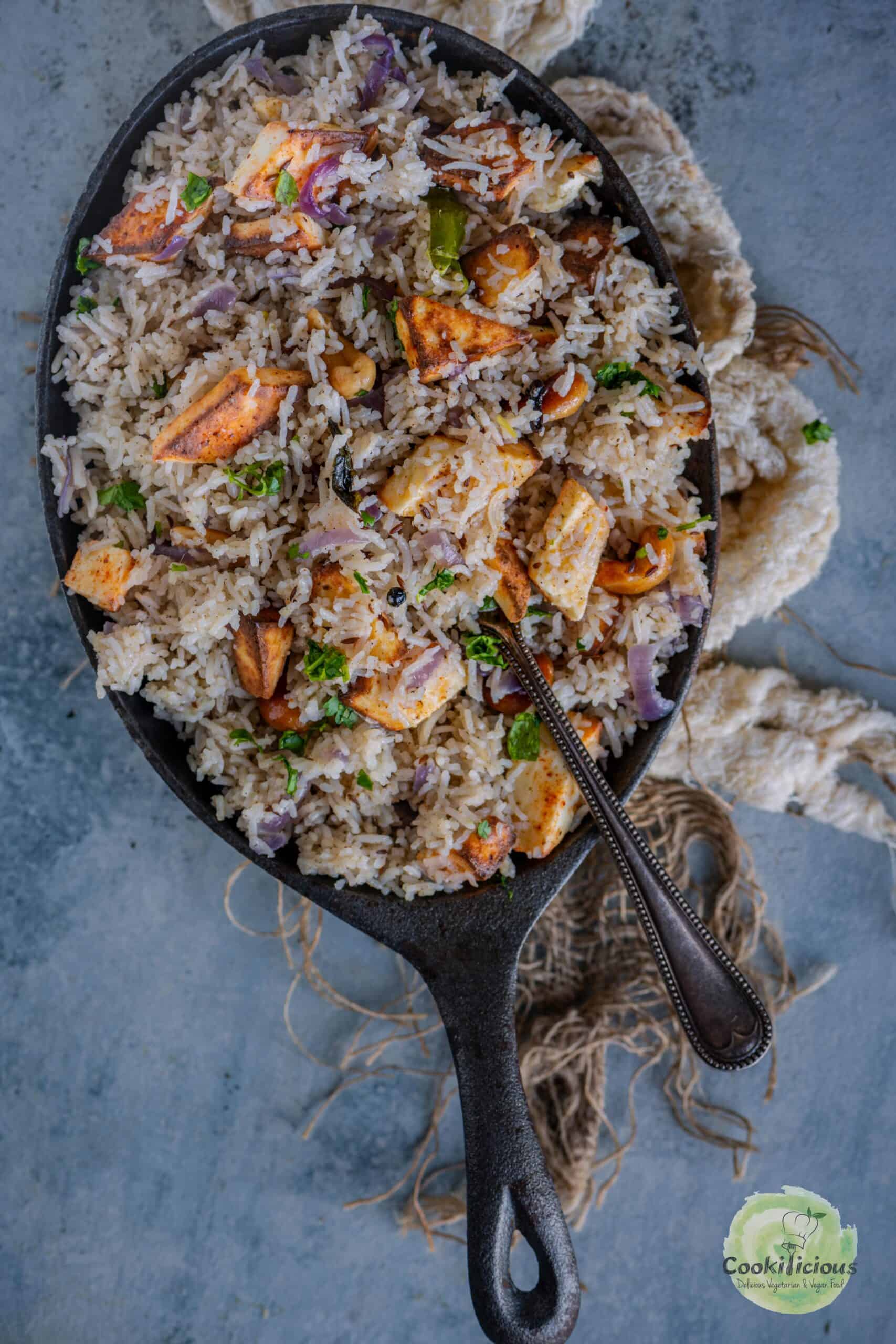 paneer rice served in an oval platter with a spoon in it.