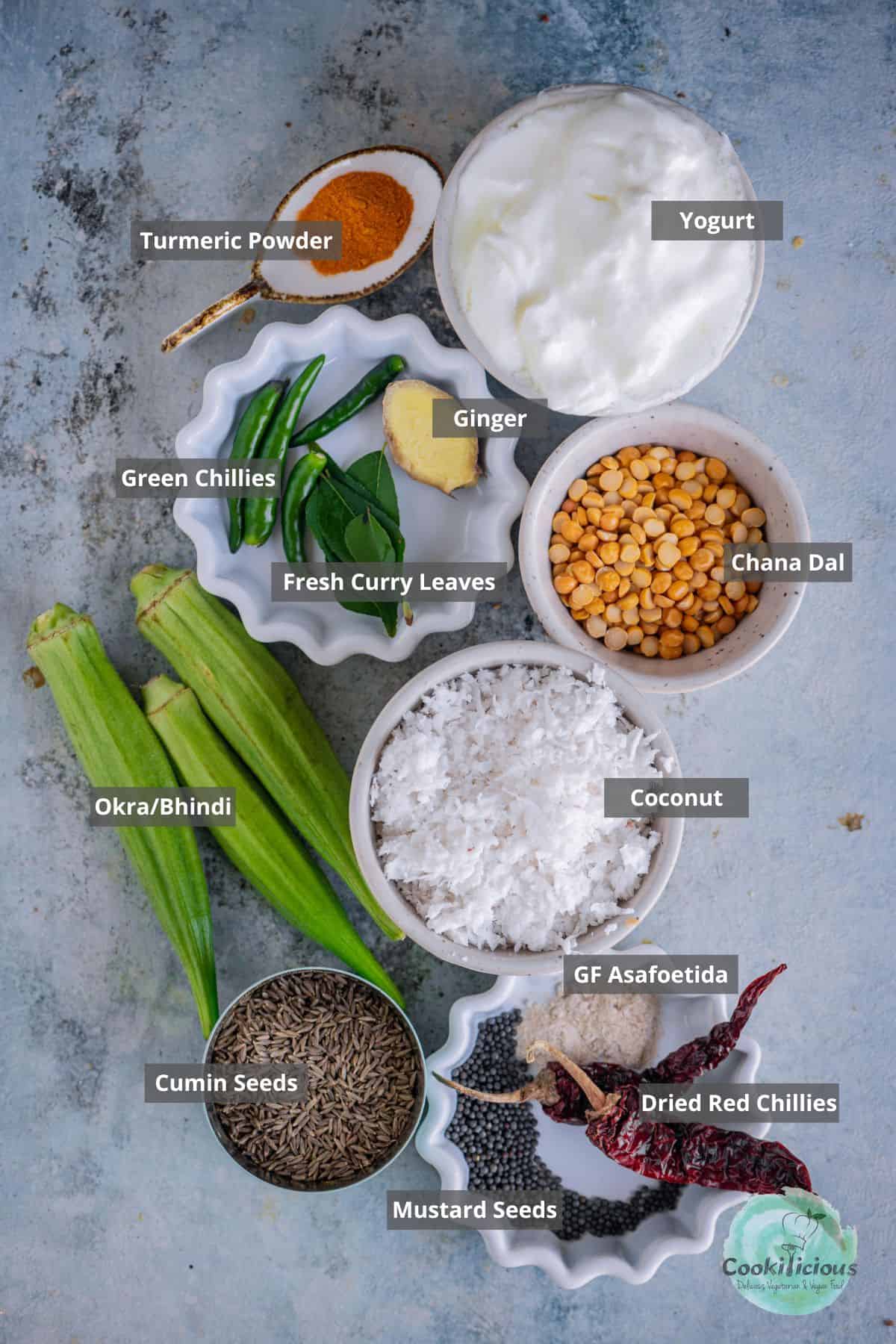 All the ingredients needed to make Vendakkai Mor Kuzhambu placed on a table with labels on them.