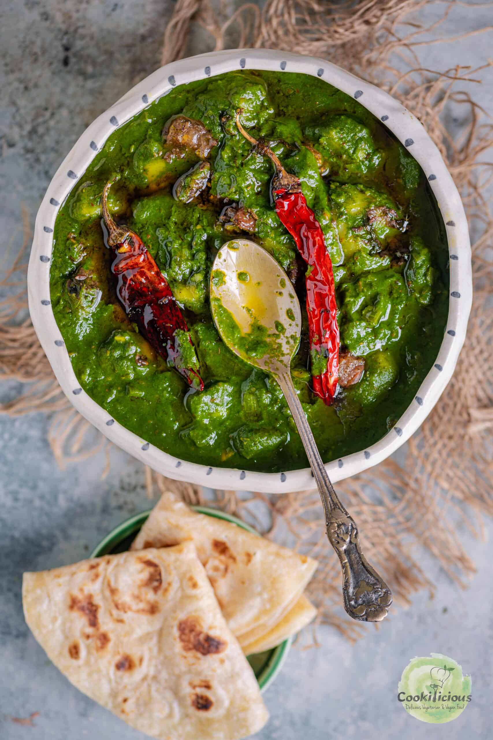 A rustic serving of Aloo Palak garnished with red chilies for an extra flavor boost.