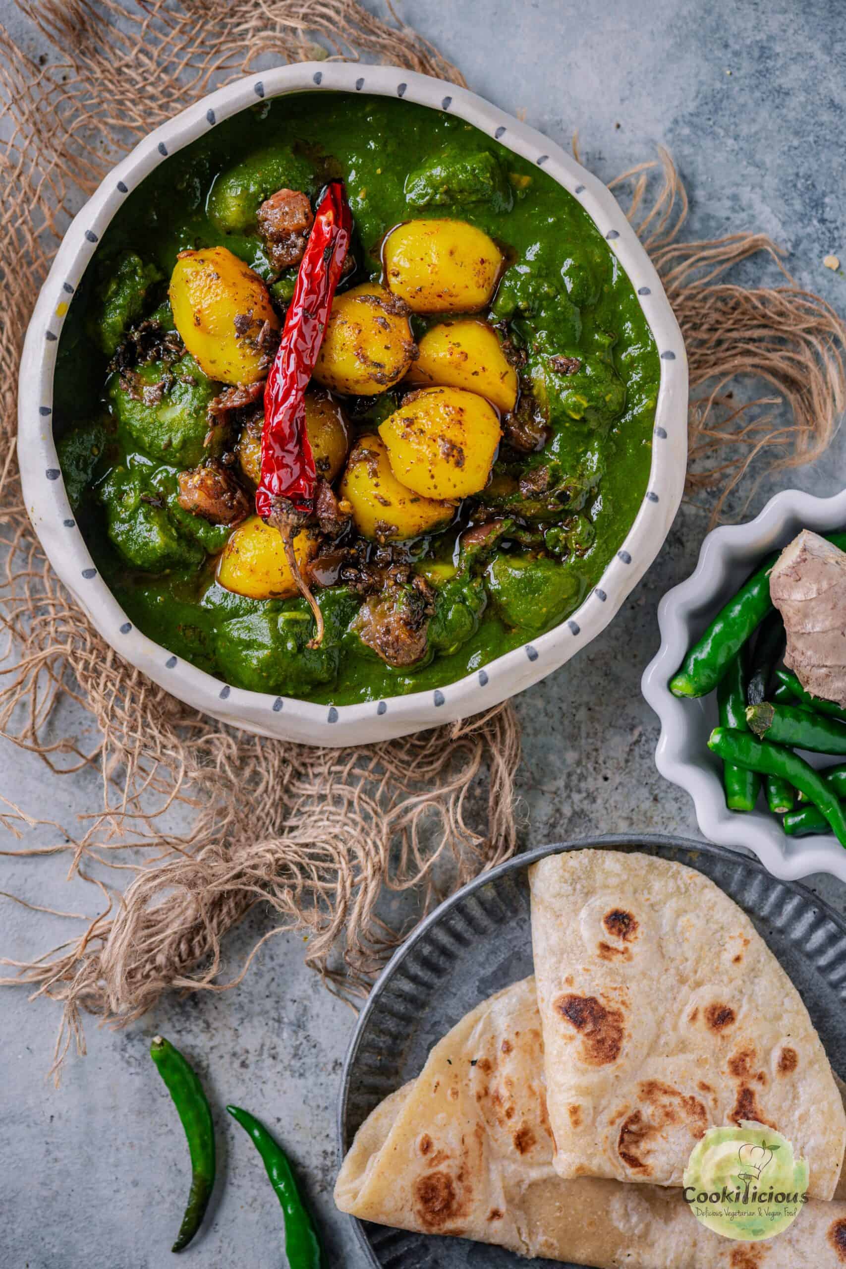 A bowl of Aloo Palak curry with golden potatoes in a creamy spinach gravy, served with chapati on the side.