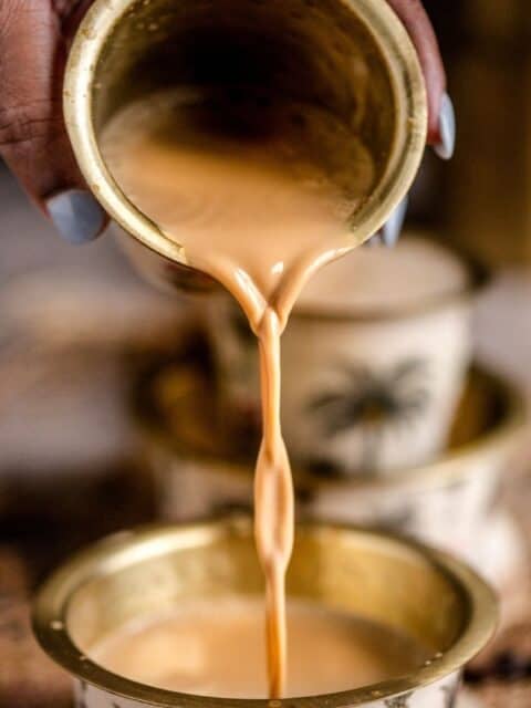 A hand pouring South Indian Filter Coffee from a metal glass into the davara and text at the top.