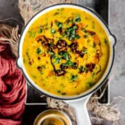 Methi Dal Tadka served in a round platter with tadka on top.