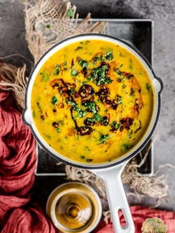 Methi Dal Tadka served in a round platter with tadka on top.