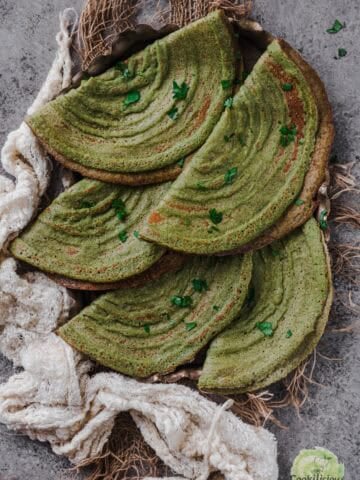 A stack of freshly made Pesarattu, showcasing their crispy texture.