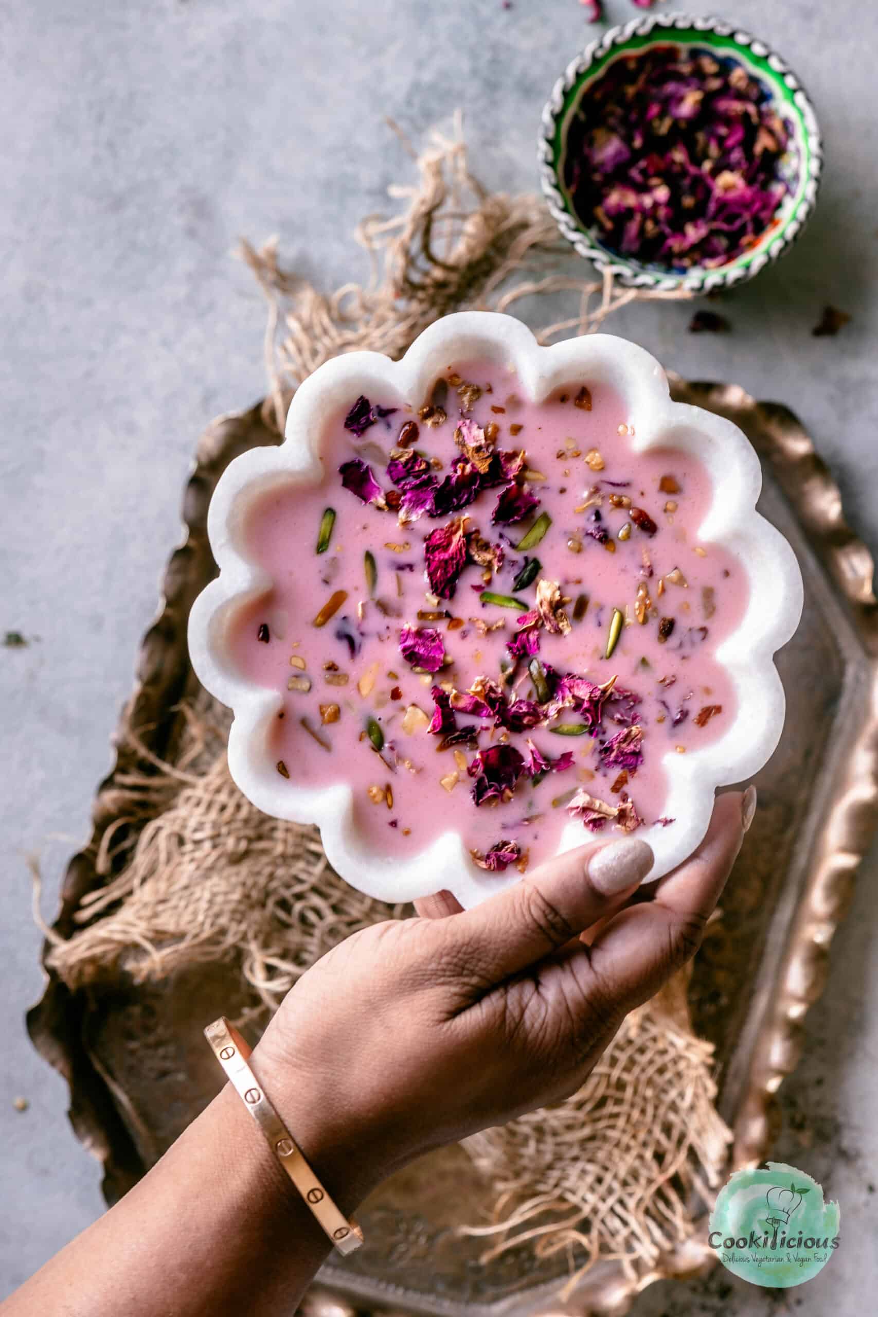 A hand placing a bowl filled with Vegan Rose Basundi on a tray.