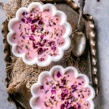 2 bowls of Basundi dessert served in a tray with a spoon on the side.