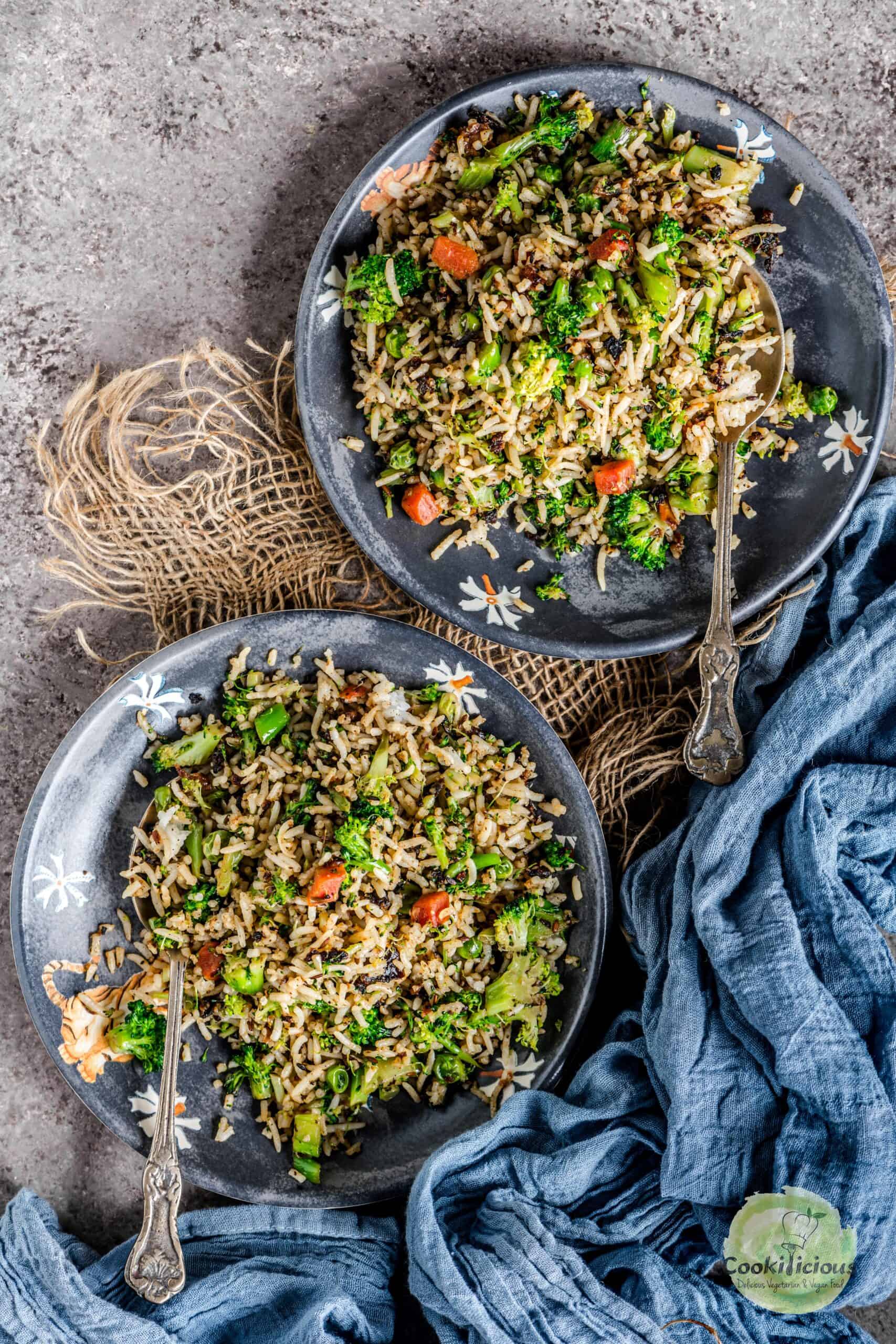 Broccoli fried rice served in 2 plates with spoons in them.