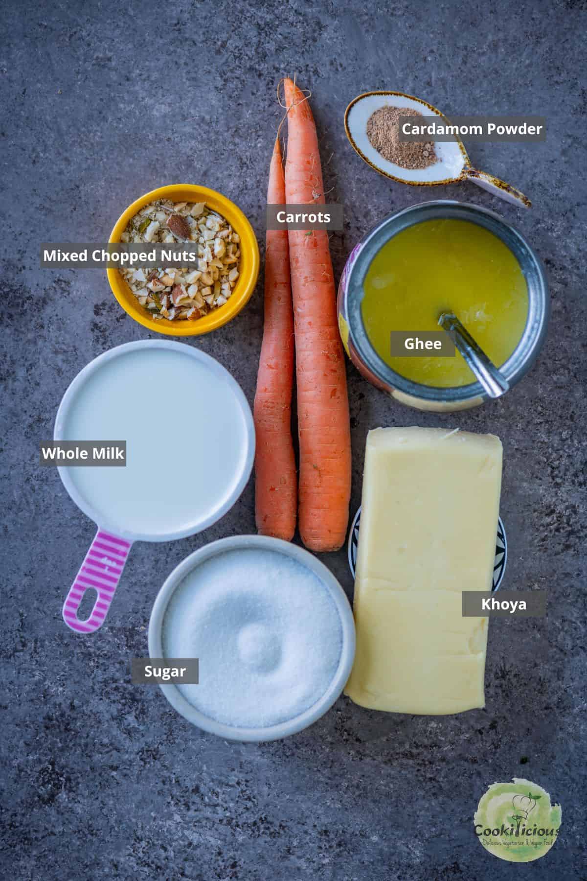all the ingredients needed in the gajar ka halwa recipe, placed on a table with labels on them.