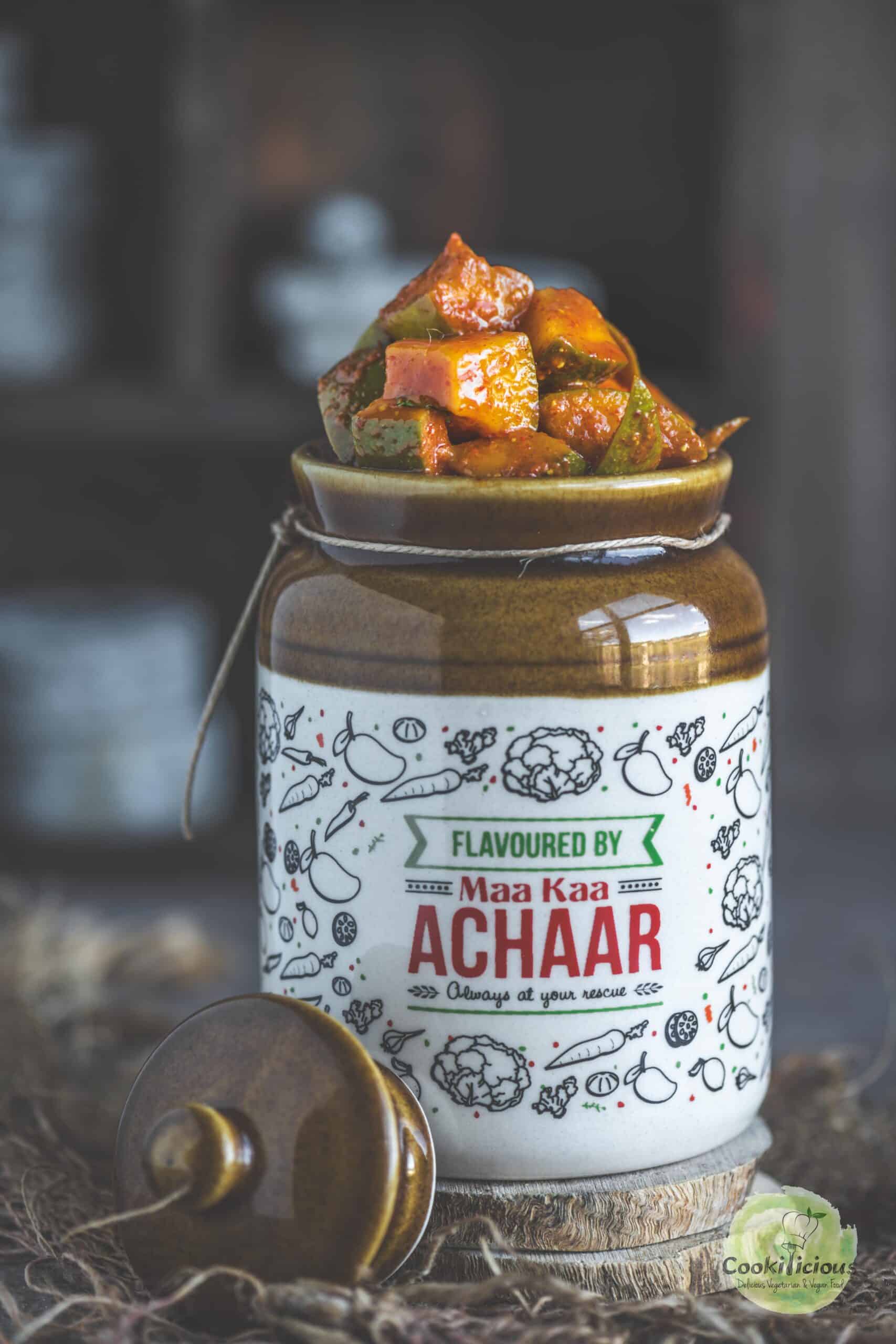 South Indian raw mango pickle (Manga Urugai) in a ceramic jar with mustard seeds and red chili.