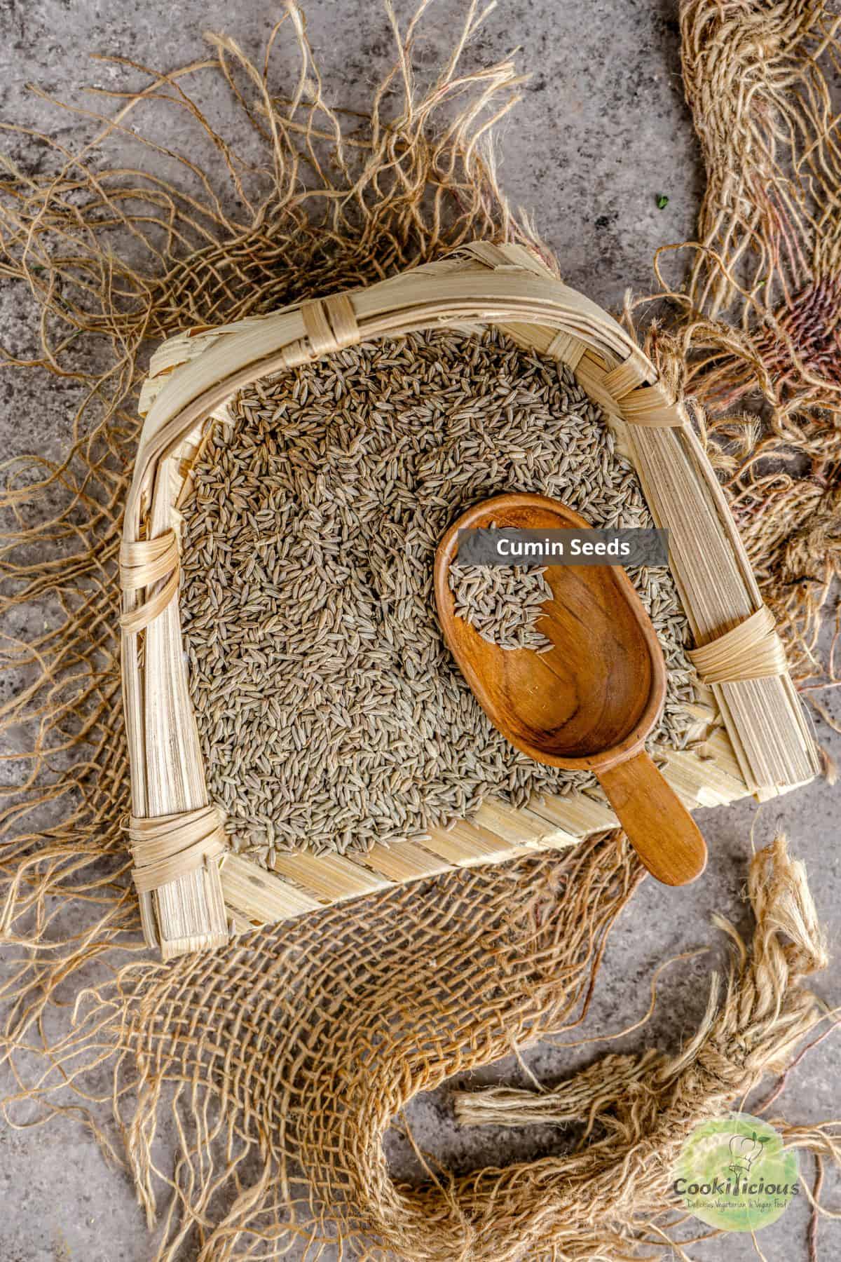Cumin seeds placed on a tray with a wooden spoon in it.