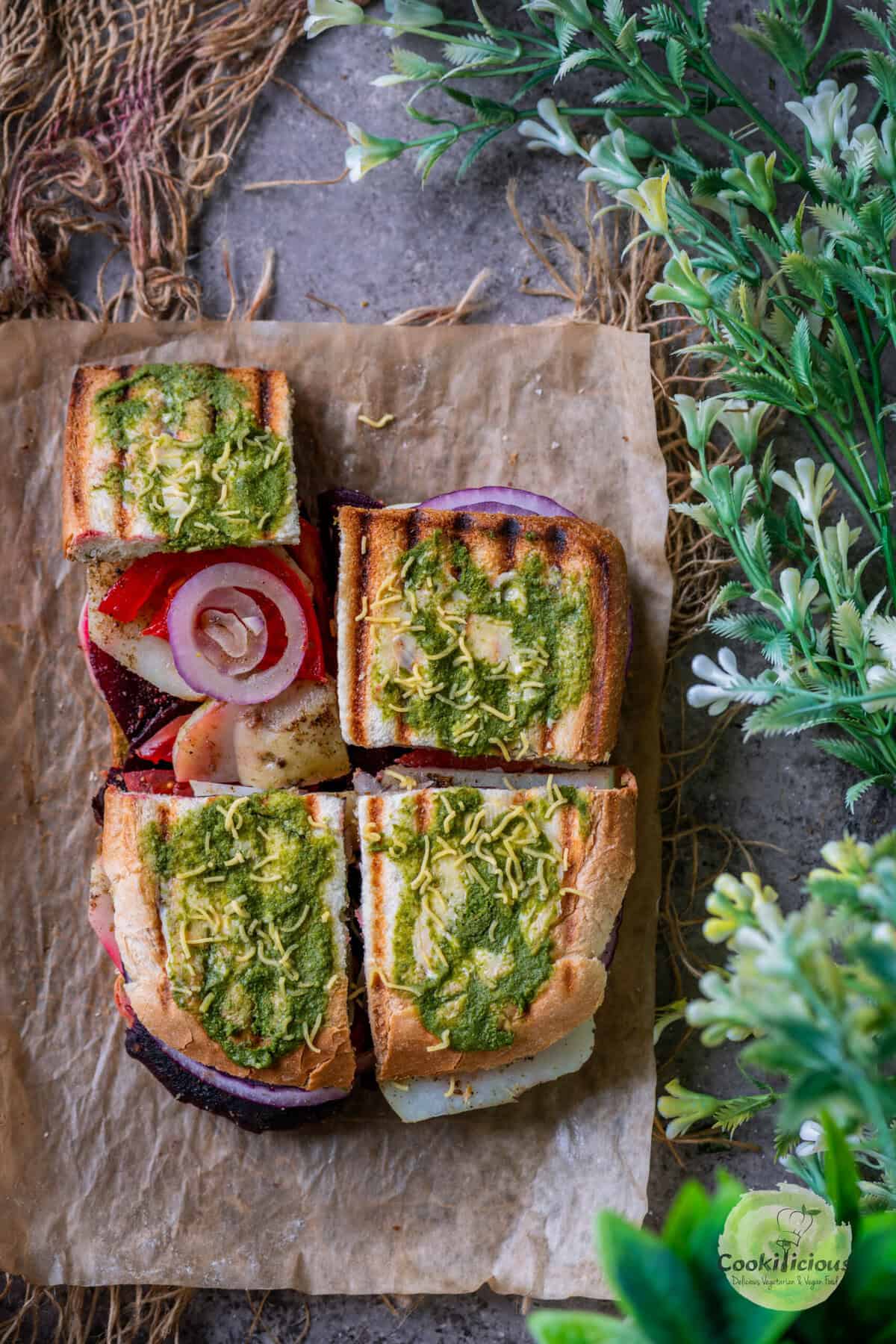 Grilled Bombay Sandwich served on a paper with sev and chutney smeared on top of the bread.