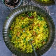 South Indian Lemon Rice served in a brass plate with a spoon in it.