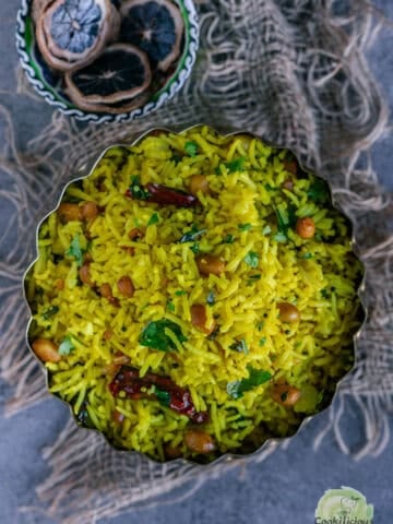 Authentic Indian Lemon Rice with peanuts, and curry leaves served in a plate.