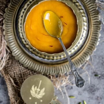 Aamras served in a brass bowl and spoon in it.