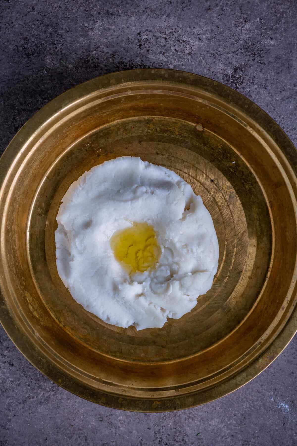 Kneading warm kozhukattai dough with gingelly oil on a plate.