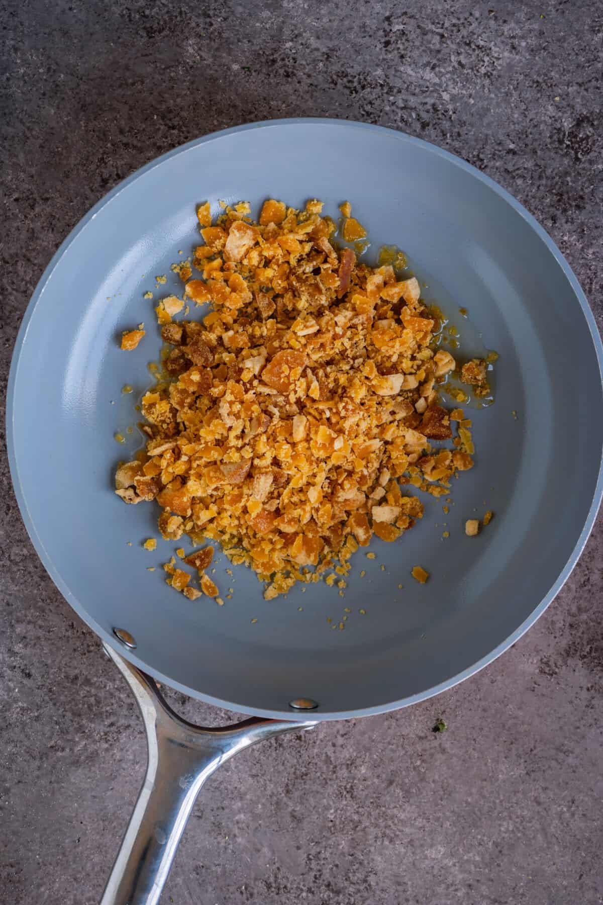 Shredded jaggery added to melted ghee in a pan.