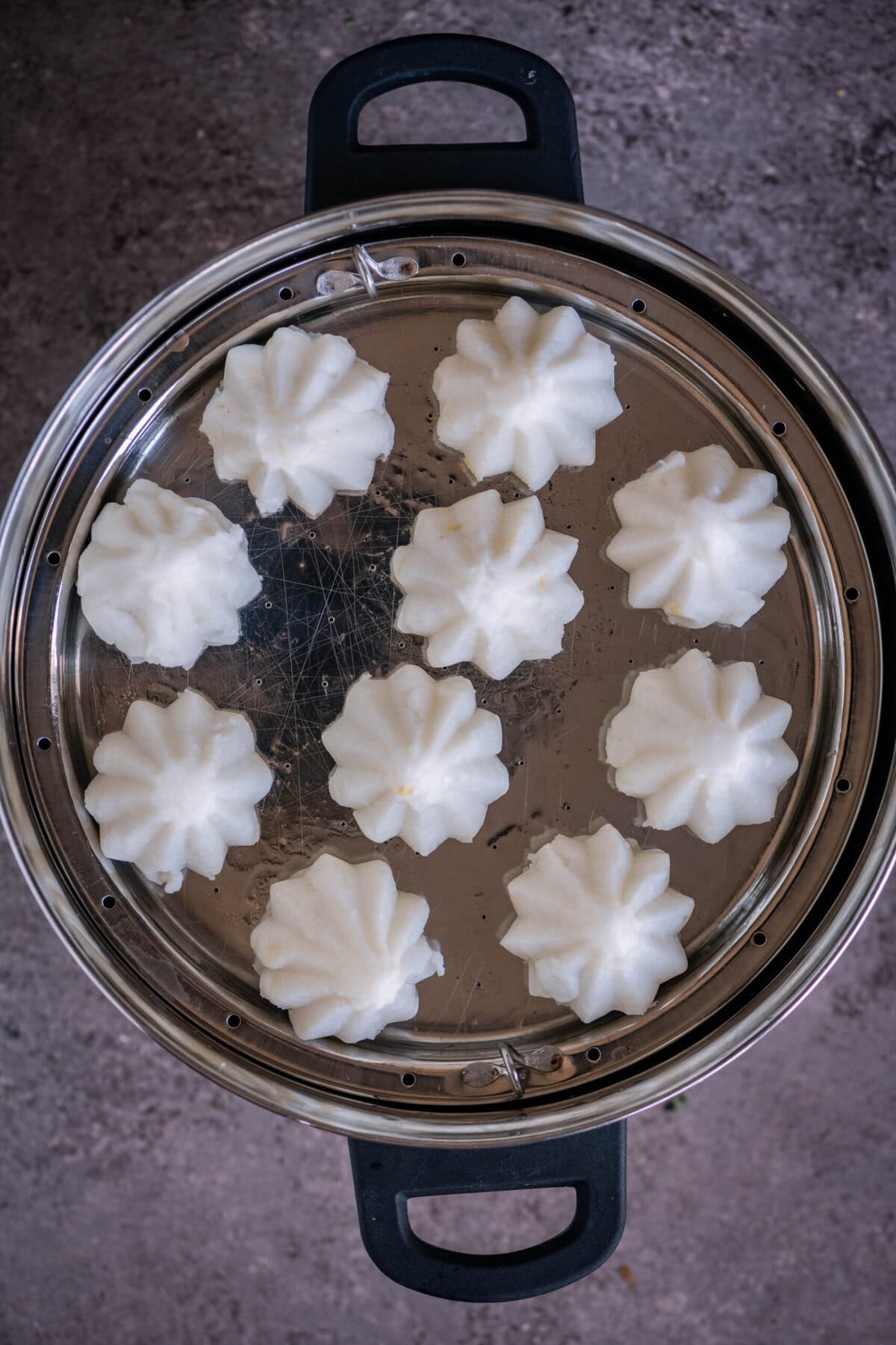 Steamed kozhukattai arranged on a greased steamer plate.