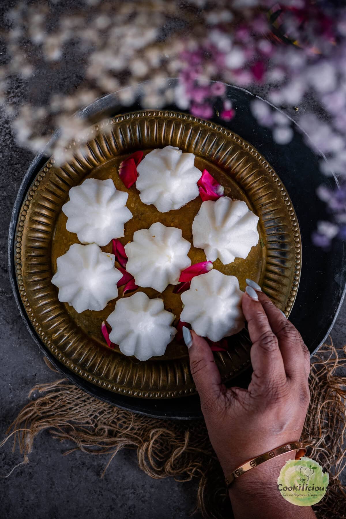 A hand picking up one kozhukattai from a plate.