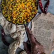 A hand holding a pan filled with Kothavarangai Paruppu Usili.