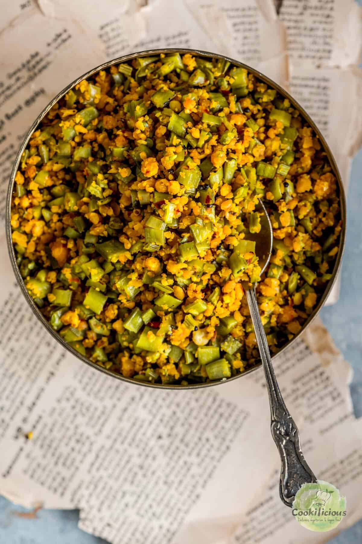 A bowl of stir fried Kothavarangai Paruppu Usili with a spoon in it.