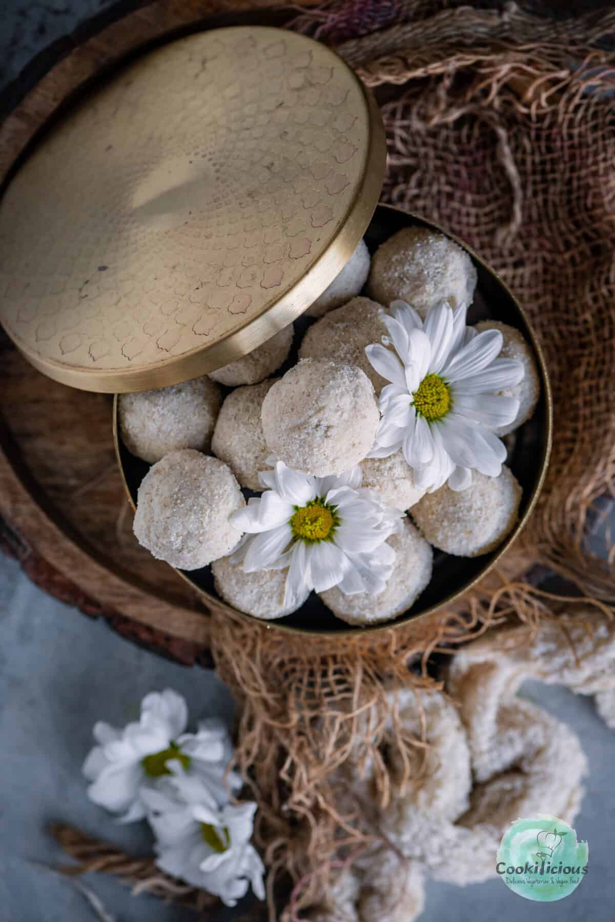 Delicious vegan and gluten-free Rava Laddu (Rava Ladoo) served in a brass dabba.