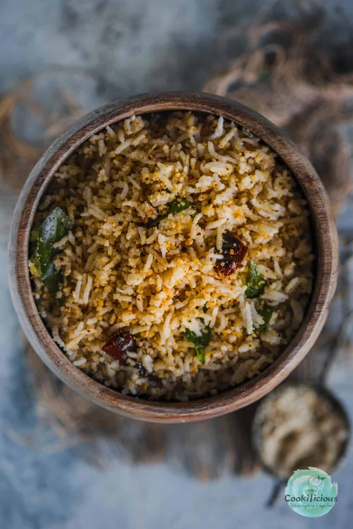 Close-up of steaming hot Sesame Rice (Ellu Sadam) garnished with fresh curry leaves and mustard seeds.