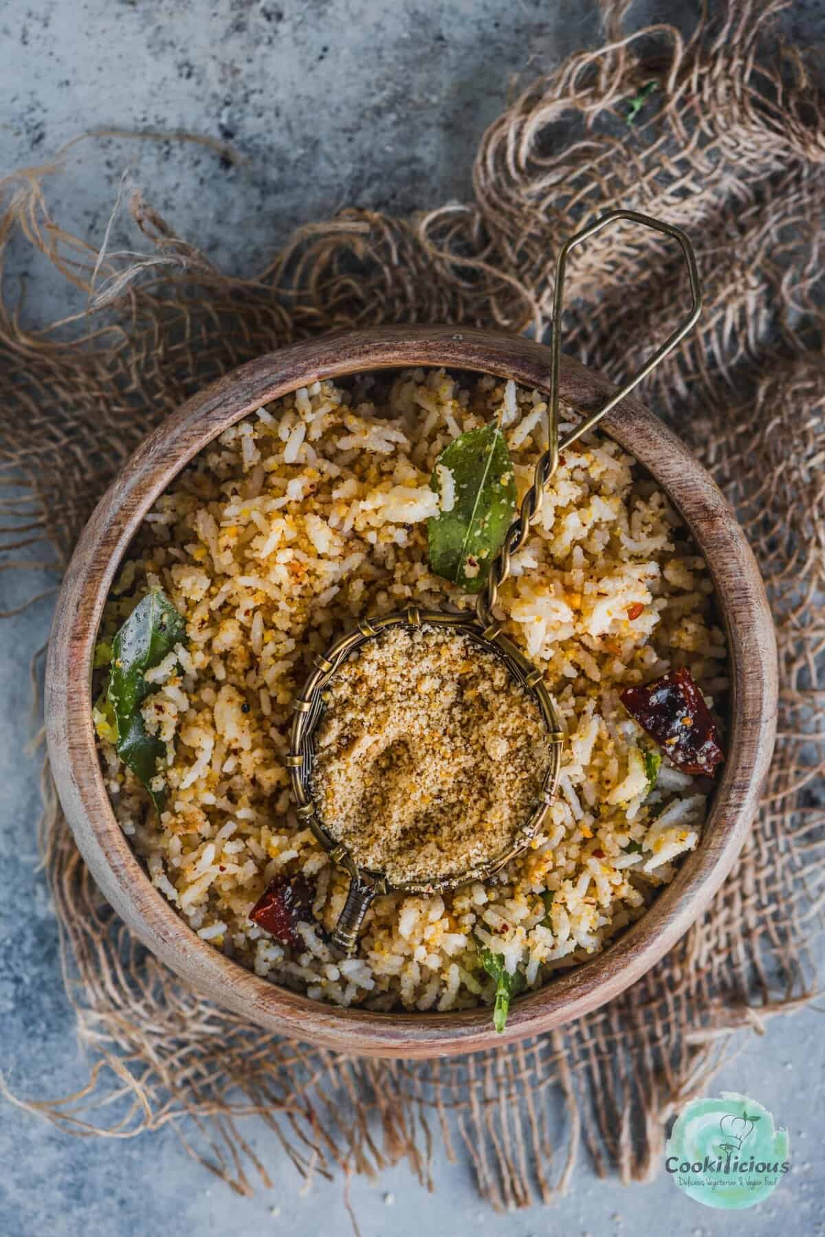 a bowl of sesame rice served with a small bowl filled with ellu podi in the middle. 