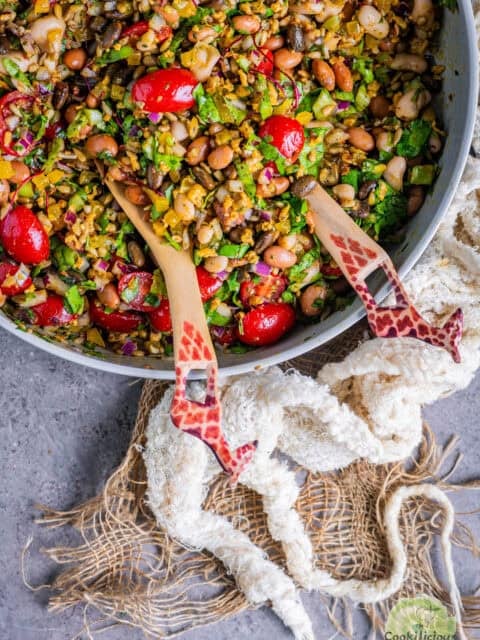 Close-up of colorful vegan Dense Bean Salad with black soybeans, pinto beans, cannellini beans, bell peppers, cherry tomatoes, and sunflower seeds.
