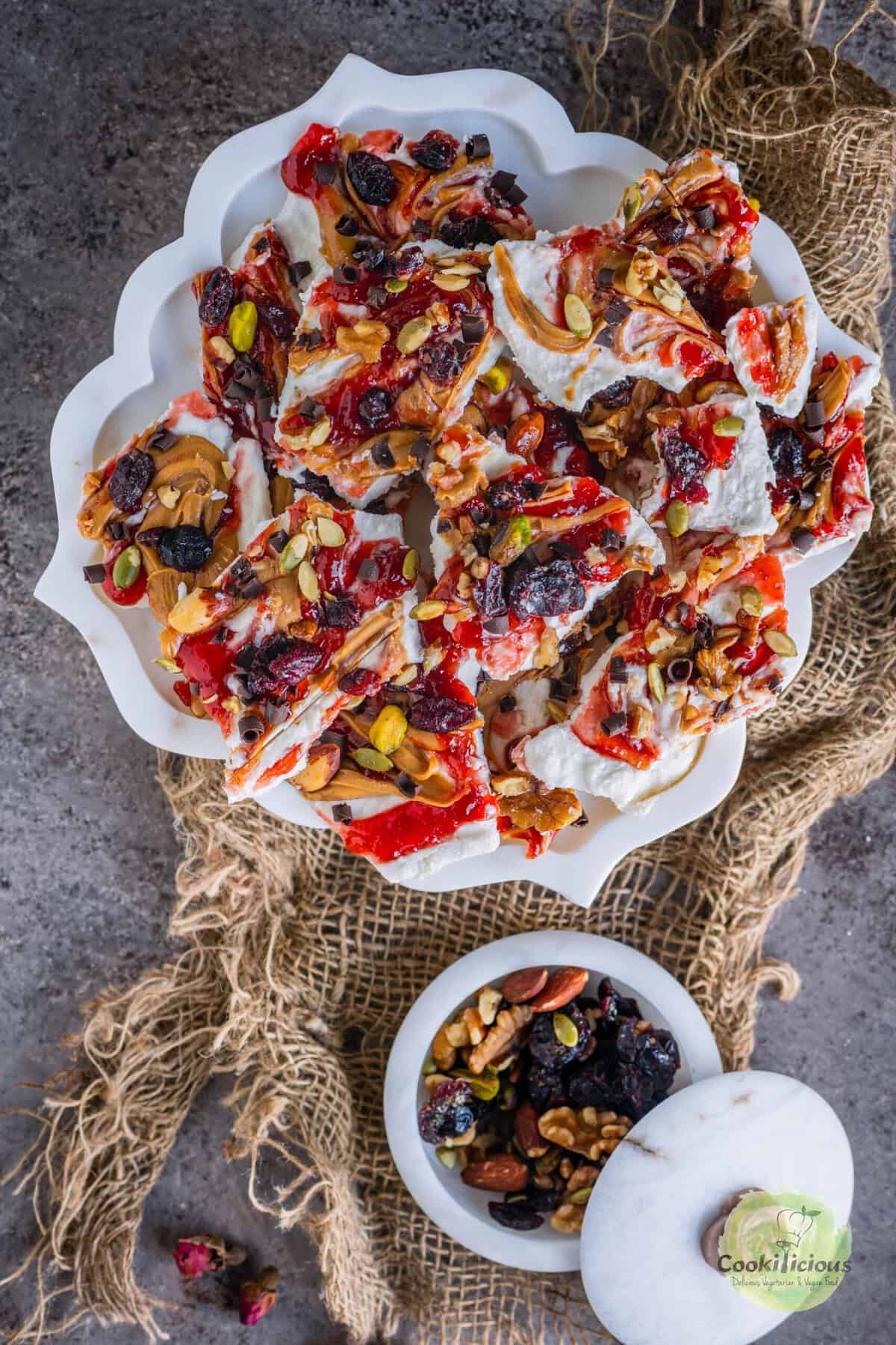 Overhead shot of viral cottage cheese bark swirled with peanut butter and strawberry jam, topped with nuts, seeds, and cranberries.