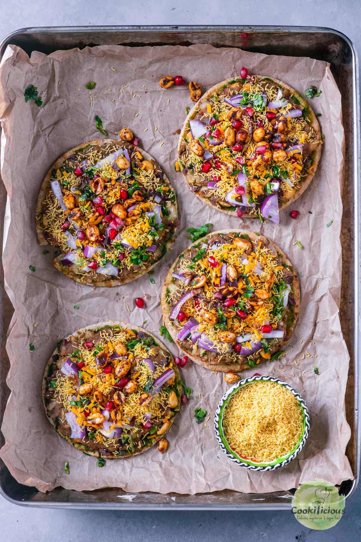 Mini pita Dabeli Pizza with spicy dabeli filling, crunchy sev, pomegranate, and melted vegan cheese – quick and easy Indian street food recipe.