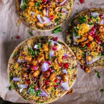 Cheesy Dabeli Pizza on mini pita bread with dabeli masala, pomegranate seeds, spiced peanuts, and crispy sev - easy Indian street food fusion snack.