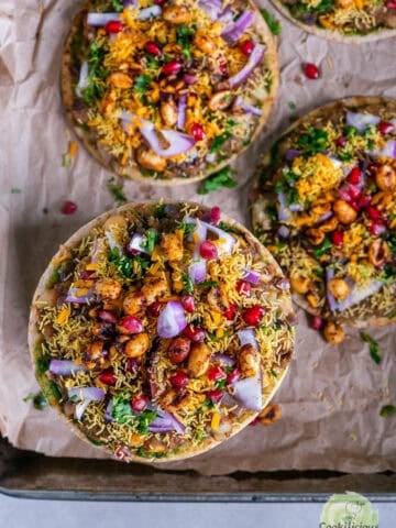 Cheesy Dabeli Pizza on mini pita bread with dabeli masala, pomegranate seeds, spiced peanuts, and crispy sev – easy Indian street food fusion snack.