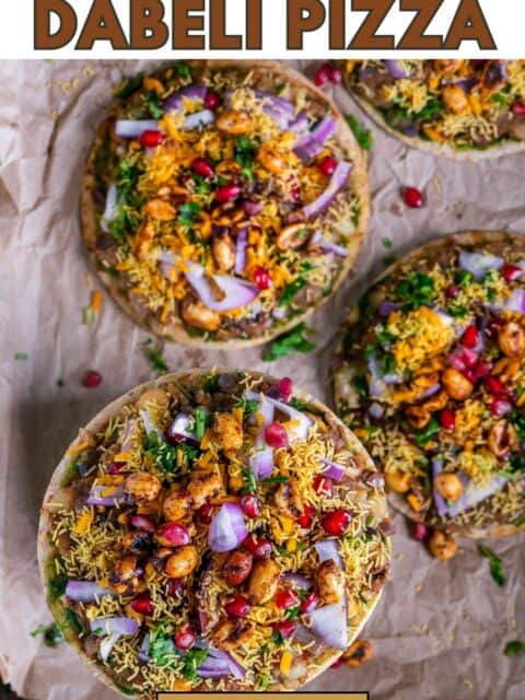 Quick and delicious Dabeli Pizza with mini pita bread, dabeli masala, crispy sev, pomegranate seeds, spiced peanuts, and vegan cheese topping and text at the top and bottom.