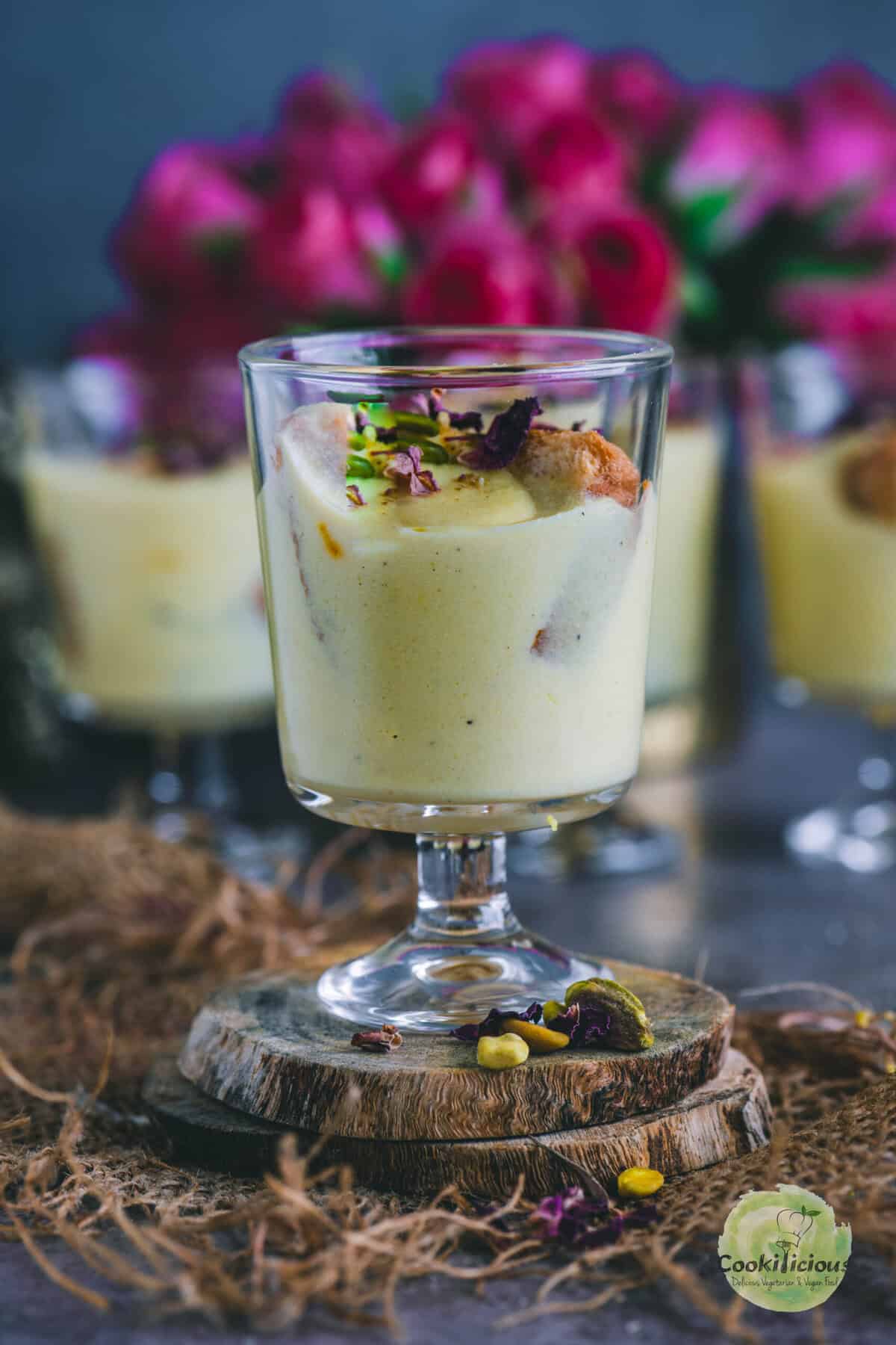 Close-up of Rabdi Cheesecake garnished with chopped pistachios and saffron strands, showing creamy ricotta and crunchy rusk base.