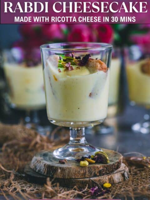 Individual serving of instant Rabdi Cheesecake in a glass, layers of ricotta rabdi and rusk visible, decorated with nuts and saffron and text at the top and bottom.