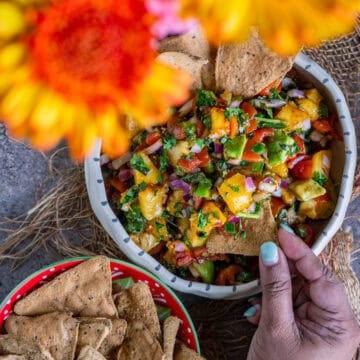 Vegan peach salsa served in a salad bowl with diced peaches, tomatoes, bell peppers, and avocado.